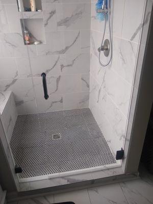 Custom shower upgrades with custom pan and shower doors with a bench