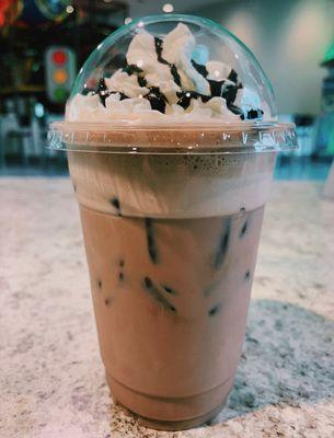 A café mocha over ice with whipped cream and chocolate drizzle