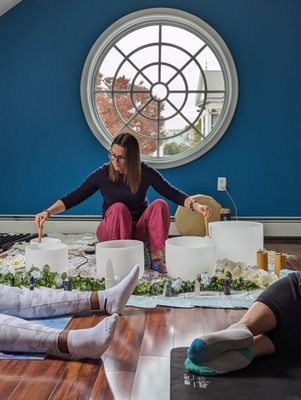 Playing crystal singing bowls at a group sound bath