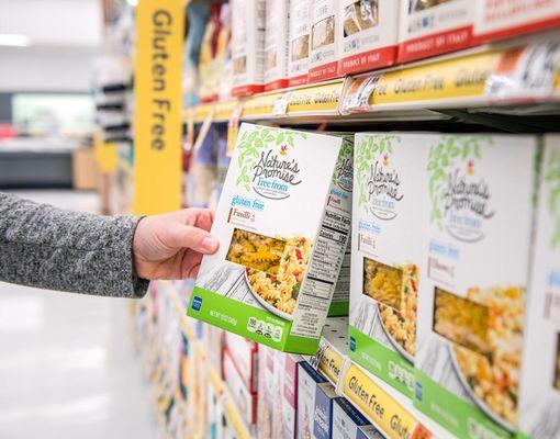 Tight shot of customer picking up a Nature's Promise item off the shelf.