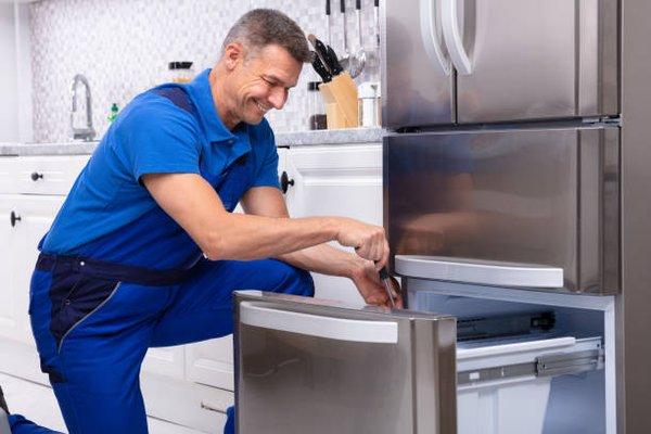 Appliance repairman servicing a refrigerator.