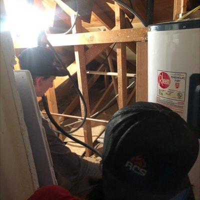 Wes & Carl working in a super tight crawl space just to get to this old water heater drained before installing the new one.