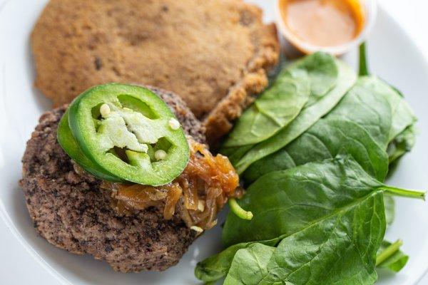 Paleo Beef Burger 
 with caramelized onions and chipotle mayo. Served on a bed of organic spinach with a low carb almond-flax bun