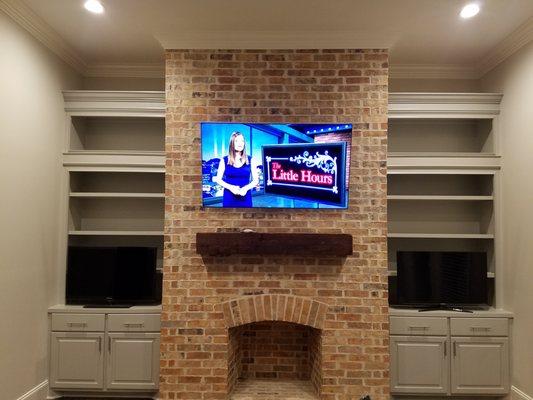 TV mounted on brick surface above fireplace