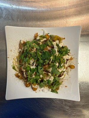 Samosa Chaat,  Chopped vegetable samosa with chick peas, mint, tamarind and white sauce.