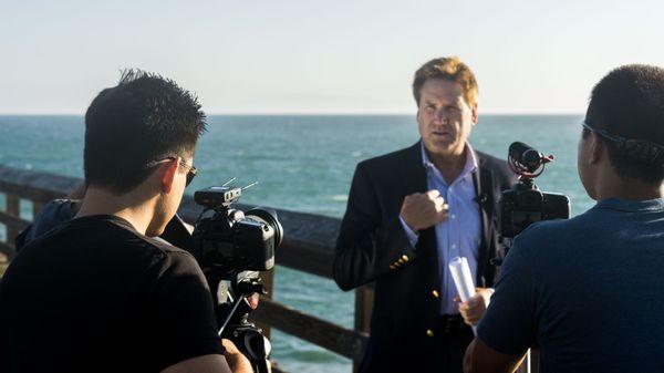 Crew on pier filming reporter.