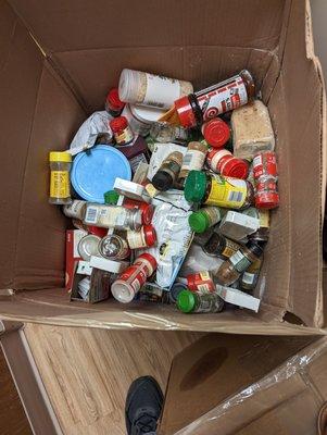 Kitchen spices thrown in a box. Multiple glass bottles broken.