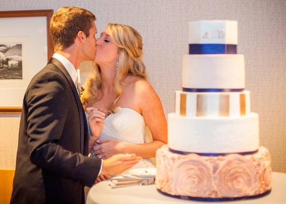 Fondant wedding cake.  Gilded stripes and monogram with edible gold leaf.  Fondant ruffle rosettes and hand-piped lace details.