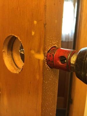 Preparing for a tubular lock installation on a wood door.